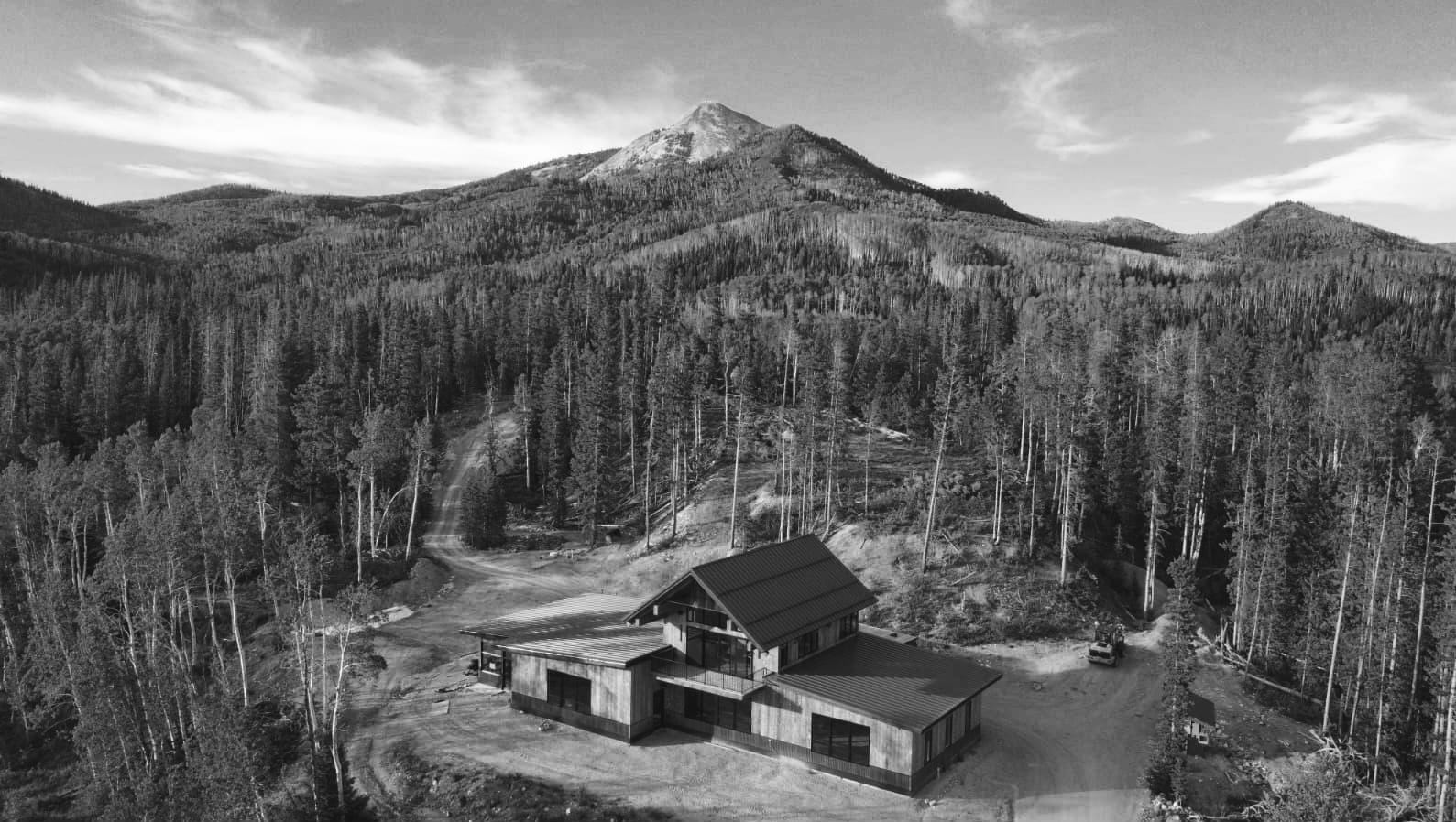 Aerial view of a mountain home surrounded by forest in the Mountain West